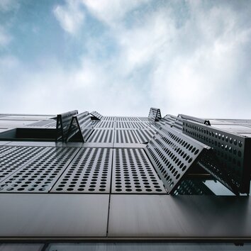 Blick in den Himmel entlang einer perforierten Metall-Fassade