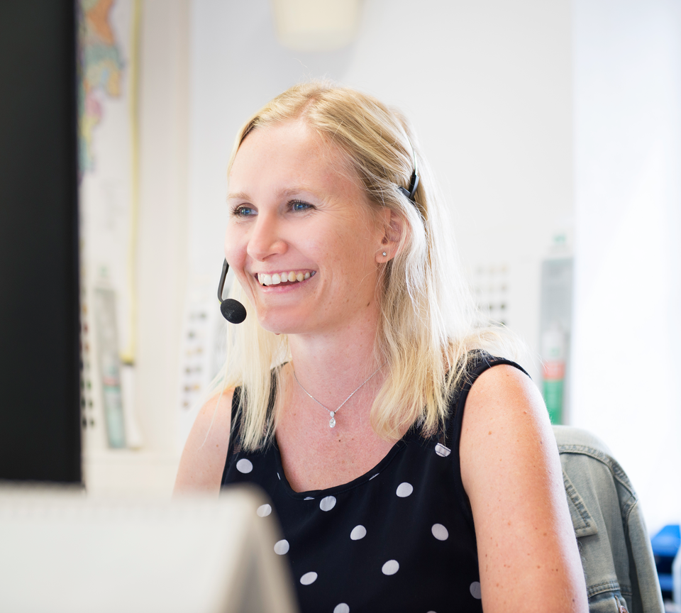 Blonde Dame beim Telefonieren mit Headset vor dem PC