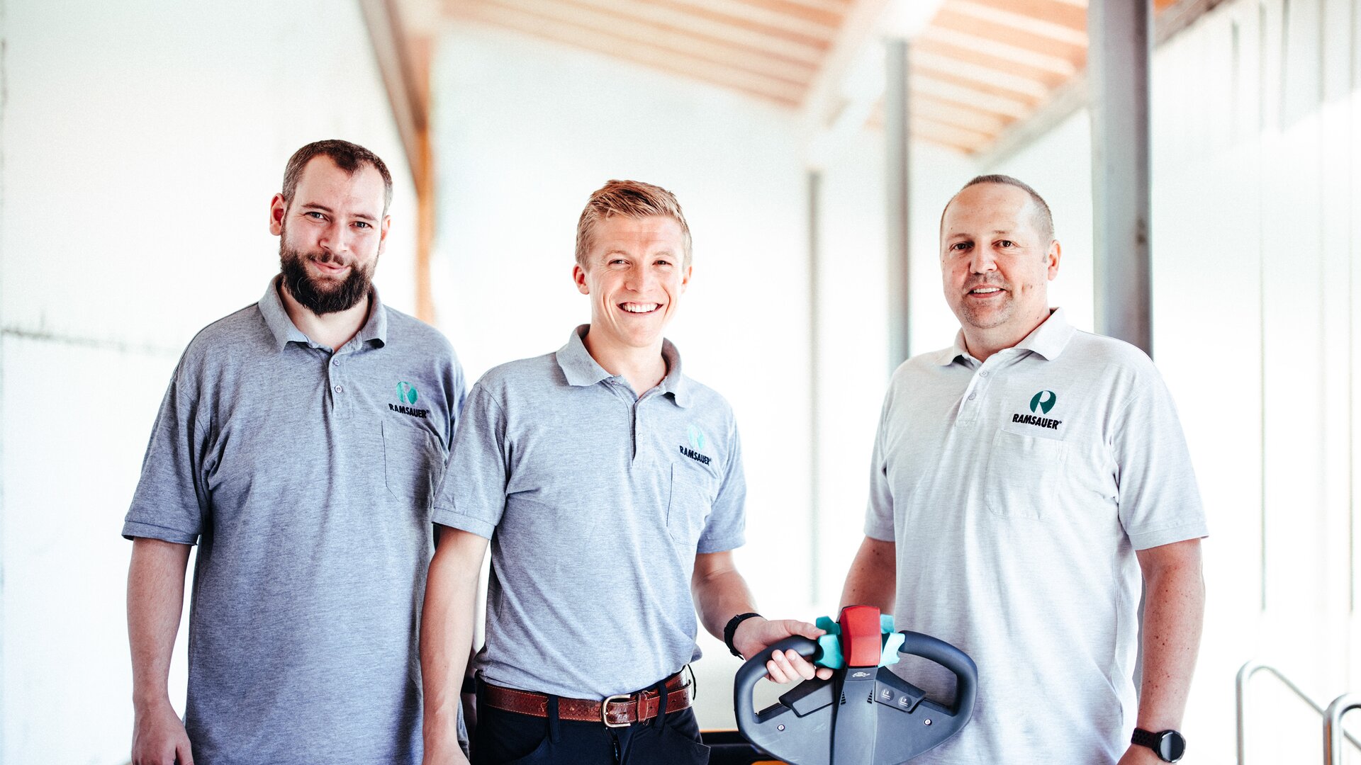 Three Ramsauer employees in grey Ramsauer shirts. 