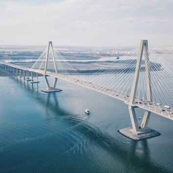 Lungo ponte moderno sul mare con stralli e pilastri romboidali.