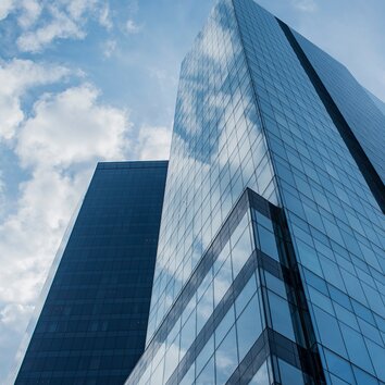 High-rise building with glass facade looking up from below, bluish-tinted image.