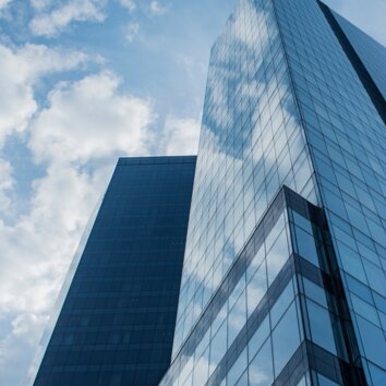 Hoog gebouw met glazen gevel van onderaf gezien, blauw getinte foto.